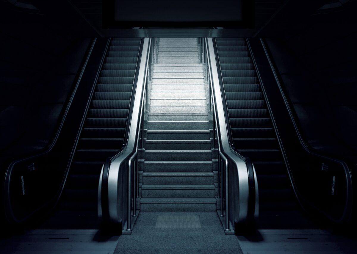 Escalera fija entre dos escaleras mecánicas en una estación.